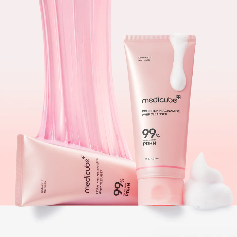 Two pink tubes of Medicube skincare product with whipped cream on a light pink background